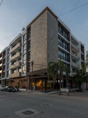 A multi-story hotel with a modern design, featuring balconies and a ground-level restaurant. - Stilvolles Apartment mit Balkon an der Quinta (Playa del Carmen)