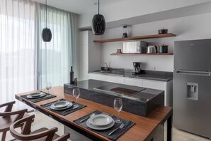 Une cuisine moderne dotée d’un îlot central, d’appareils électroménagers intégrés et d’un coin repas aménagé pour quatre personnes.