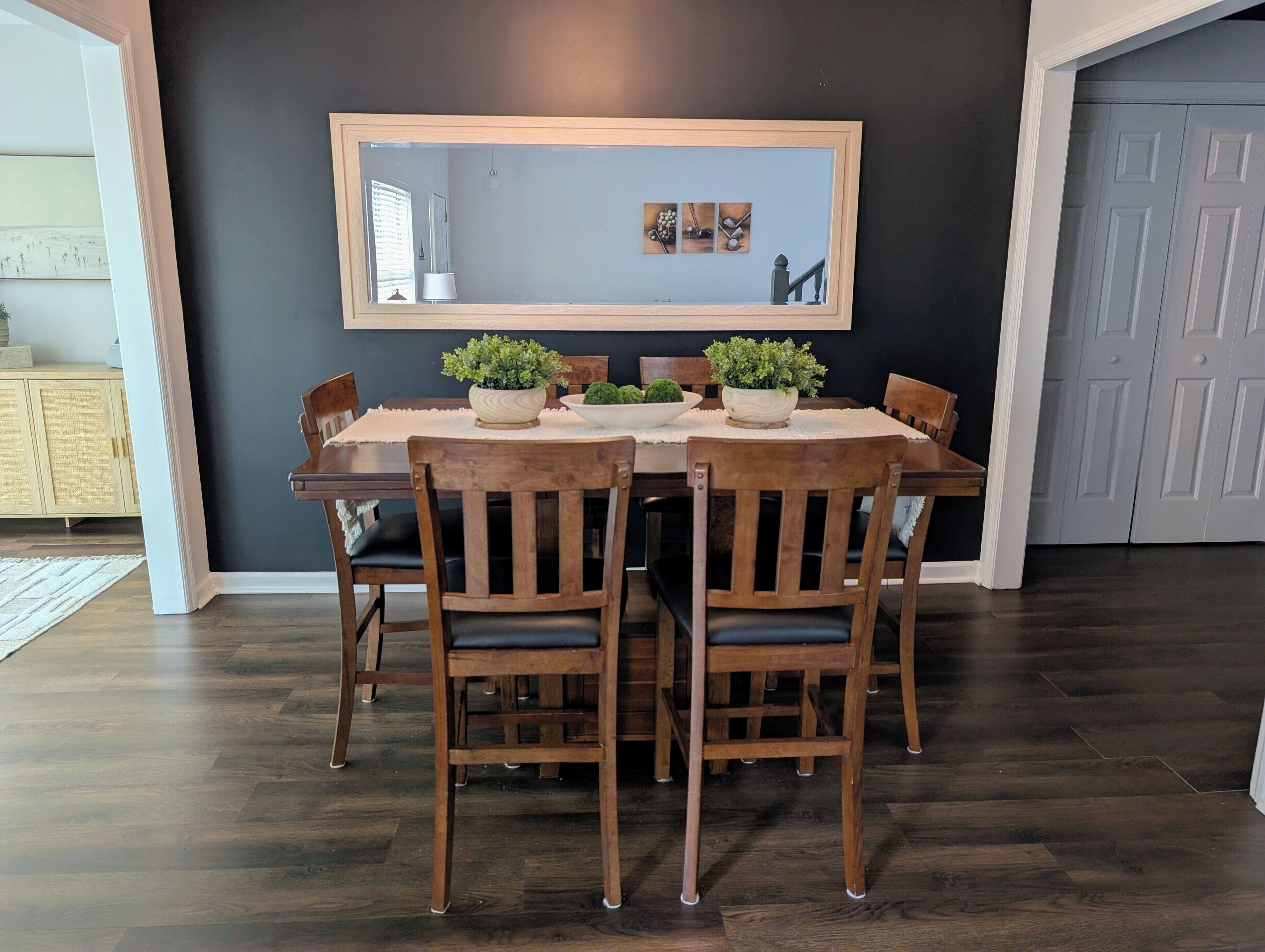 A dining area with a dark wall, a wooden table, and chairs.