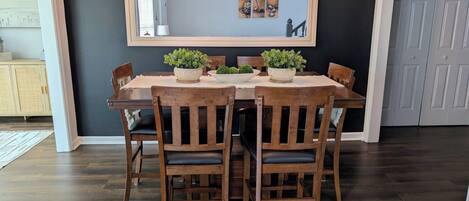 A dining area with a dark wall, a wooden table, and chairs.