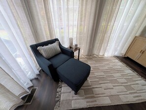 Ein modernes Zimmer mit einem dunkelblauen Sofa, einem gemusterten Kissen, einem kleinen Beistelltisch mit einer Tasse und einem Teppich mit Muster.