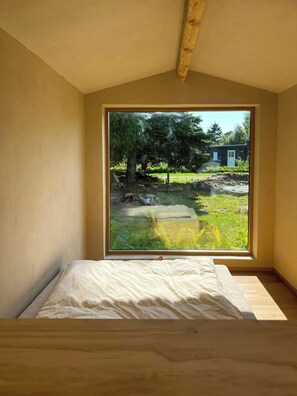 A room with a large window, a bed, and a wooden ceiling beam. - Sustainable house in wild garden near Odsherred (Højby)