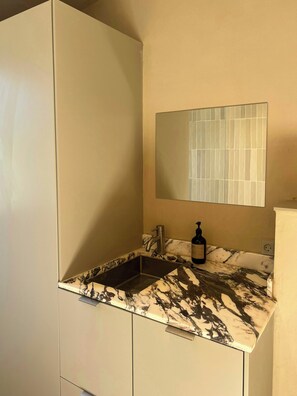 A bathroom with a sink, mirror, and a bottle of hand soap. - Sustainable house in wild garden near Odsherred (Højby)