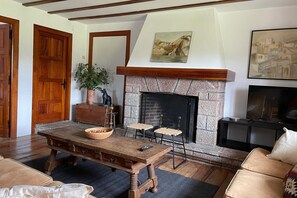 Un salon avec une cheminée, une table en bois, un canapé et un téléviseur.