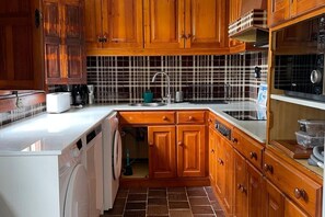 Eine Küche mit Holzausstattung, einer gefliesten Spritzschutzwand, einem Spülbecken und einem Geschirrspüler.