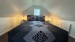 Un dormitorio con una cama, dos lámparas de noche, una ventana y una puerta.