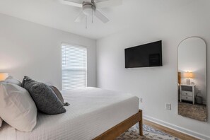 A bedroom with a bed, a ceiling fan, a TV, a mirror, and a window with blinds. - 🐾 Lost Bay Townhome 4239 | Dog Friendly | New Build + Heart of Orange Beach (Orange Beach)