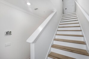 A staircase with white walls, wooden steps, and a white handrail. - 🐾 Lost Bay Townhome 4239 | Dog Friendly | New Build + Heart of Orange Beach (Orange Beach)