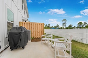 A patio with a covered grill, outdoor seating, and a wooden fence. - 🐾 Lost Bay Townhome 4239 | Dog Friendly | New Build + Heart of Orange Beach (Orange Beach)