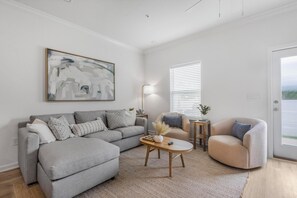 A living room with a grey sofa, a round coffee table, and a beige armchair. - 🐾 Lost Bay Townhome 4239 | Dog Friendly | New Build + Heart of Orange Beach (Orange Beach)