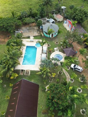 A residential property with a swimming pool, a covered outdoor area, and a house with a red roof. - Cabaña Elian (Higüey)