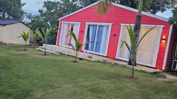 A red building with white-framed windows and a small lawn area.
