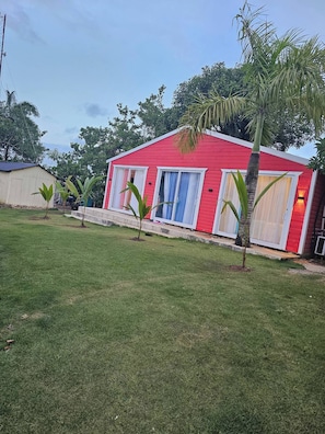 A red building with white-framed windows and a small lawn area.