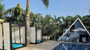 A swimming pool with a tiled edge, surrounded by lounge chairs and a covered seating area. - Cabaña Elian (Higüey)