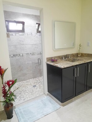 Ein Badezimmer mit Dusche, Waschbecken und Spiegel.