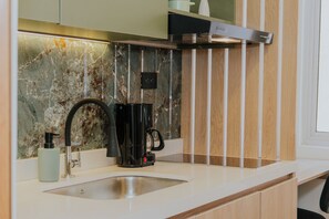 Eine moderne Küche mit Marmor-Spritzschutz, einer Kaffeemaschine und einem Edelstahl-Spülbecken.