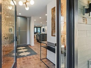 Una cocina moderna con una isla central, un comedor con banco y un pasillo que conduce a una sala de estar.