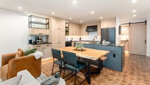 A modern kitchen with a central island, wooden dining table, and chairs. - Luxury Condo E1 + Hot tub at Wapato Point Chelan (Manson)