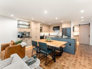 A modern kitchen with a central island, wooden dining table, and chairs. - Luxury Condo E1 + Hot tub at Wapato Point Chelan (Manson)