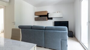 A modern living room with a grey sectional sofa, a flat-screen TV, and built-in shelving. - A welcoming and spacious apartment of approximately 130 sqm—perfect for 8 guests—located within a villa in an exclusive neighborhood of Marina di Pietrasanta, bordering Forte dei Marmi.Its strategic location allows you to reach the sea in just 7 minu (Marina di Pietrasanta)