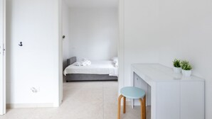 Ett minimalistiskt rum med en säng, ett skrivbord och en stol.