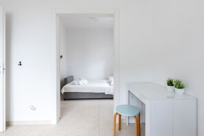 Ein schlicht eingerichtetes Zimmer mit einem Bett, einem Schreibtisch und einem Stuhl.