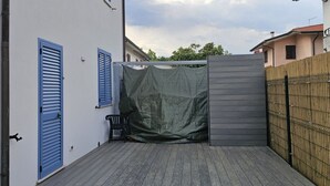 Ett takförsett utomhusområde med ett trädäck, en stol och ett staket.