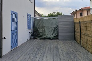 Ein überdachter Außenbereich mit Holzterrasse, einem Stuhl und einem Zaun.