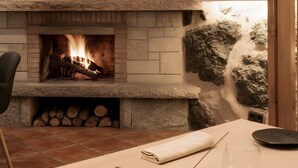 A fireplace with a stone surround, a dining table with plates, cutlery, and a glass. - Esmeralda Double Room with Interior Patio and Wi-Fi (Porqueirós)