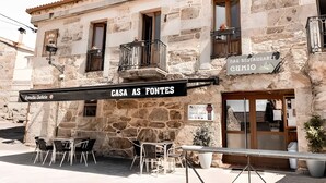 A stone building with a sign reading 'CASA AS FONTES' and outdoor seating. - Esmeralda Double Room with Interior Patio and Wi-Fi (Porqueirós)