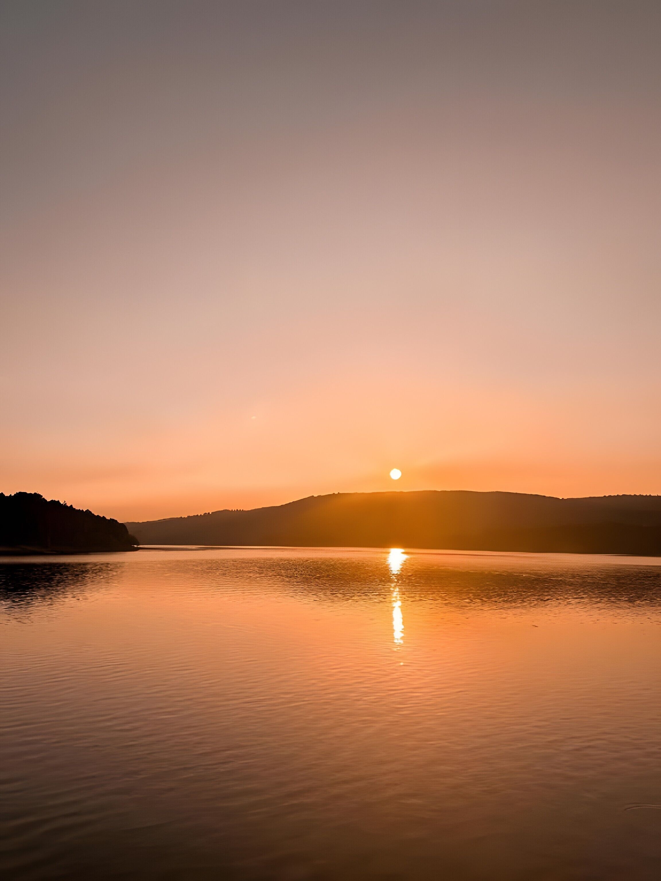Un lago tranquilo al atardecer con cielo despejado.