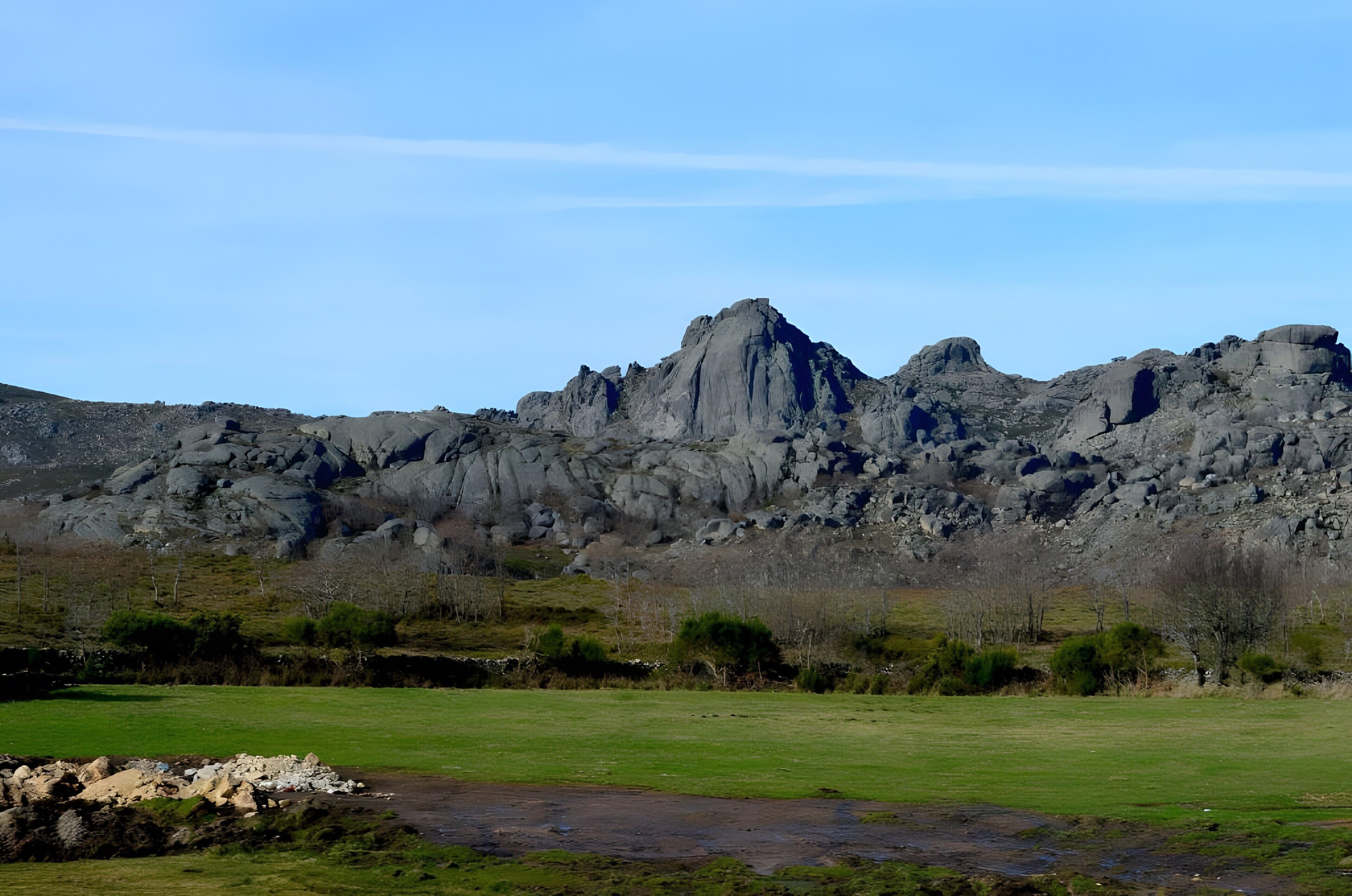 A mountainous landscape with a grassy foreground and rocky terrain.