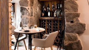A stone-walled wine cellar with a wooden wine rack, a round table with chairs, and a rustic ambiance. - Zafiro Double Room with Mountain Views, Private Balcony, and Wi-Fi (Porqueirós)