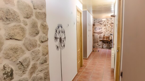 A hallway with stone walls, a tiled floor, and a door leading to a room with a stone wall. - Double Diamond Room with 2 Beds, Interior Patio, and Wi-Fi (Porqueirós)