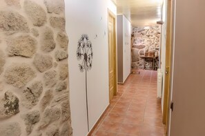 Een hal met stenen muren, een betegelde vloer en een deur naar een kamer met een stenen muur.