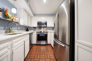 A kitchen with white cabinets, a stainless steel refrigerator, a microwave, and an oven. - 201-4thStreet-207 (Austin)