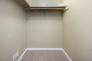 A corner room with a carpeted floor, a wooden shelf with folded towels, and a light switch on the wall. - 201-4thStreet-207 (Austin)