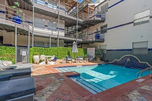 A rooftop pool area with a pool, lounge chairs, and a sign indicating a 3 ft 6 in depth. - 201-4thStreet-207 (Austin)