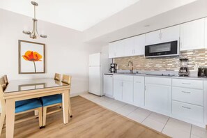 Una cocina moderna con armarios blancos, un microondas negro y una cafetera.