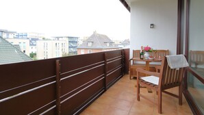 Un balcon avec une table et des chaises, une bouteille de champagne et un vase de fleurs.