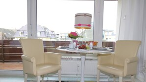 Une pièce avec deux chaises, une table, une lampe et une vue sur les bâtiments à l’extérieur.