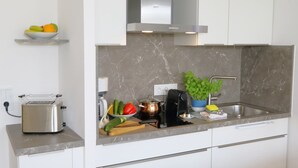 Une cuisine moderne équipée d’un grille-pain encastré, d’une bouilloire, d’un évier et d’une plante en pot.
