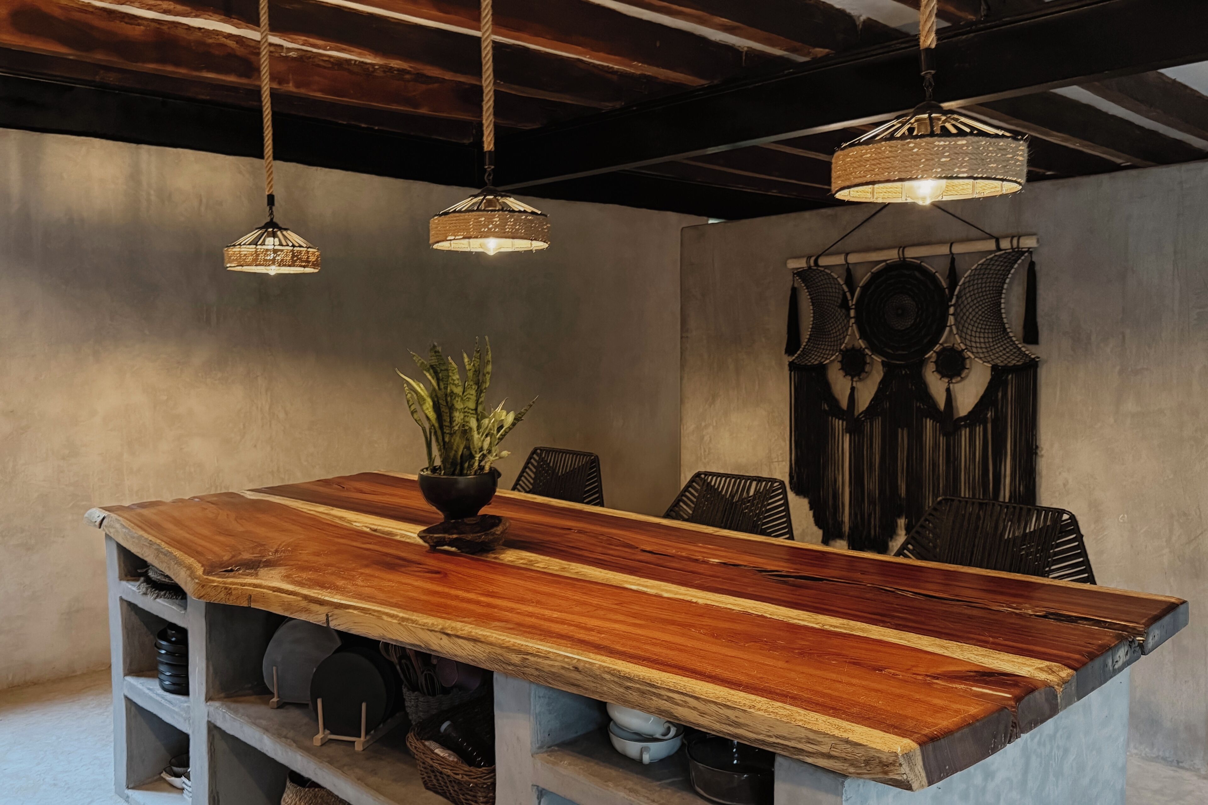 A dining area with a wooden table, hanging lights, and a wall with decorative plates.