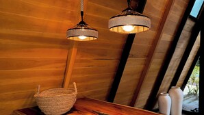 Un interior de madera con dos lámparas colgantes y una cesta tejida sobre una mesa de madera.