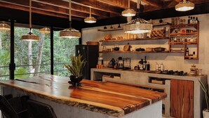 Una cocina moderna con una isla grande, luces colgantes y estantes empotrados con utensilios de cocina.