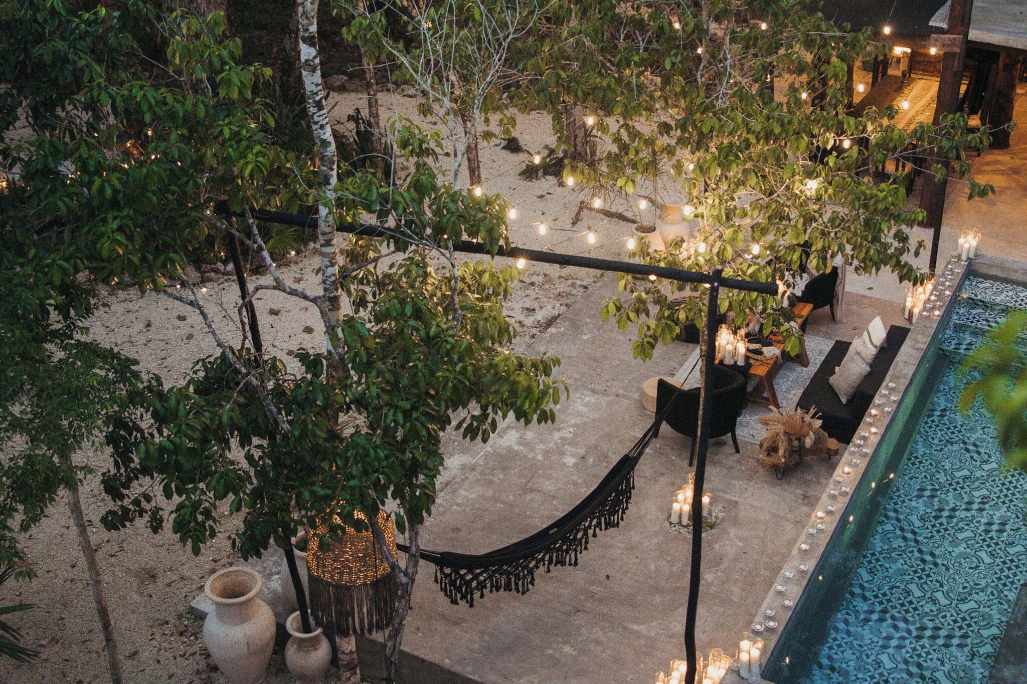 An outdoor pool area with a hammock, seating, and string lights.