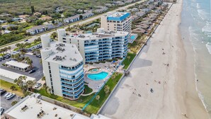 A beachfront hotel with multiple floors, a swimming pool, and a beach view. - 🏊🥽🌴Ebb Tide 406 | NSB's Finest | New Pool + Sundeck + Beach Access (New Smyrna Beach)