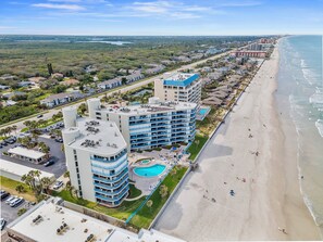 A beachfront hotel with multiple floors, a swimming pool, and a beach view. - 🏊🥽🌴Ebb Tide 406 | NSB's Finest | New Pool + Sundeck + Beach Access (New Smyrna Beach)