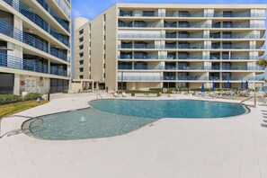 A multi-story hotel with a swimming pool, outdoor seating, and balconies. - 🏊🥽🌴Ebb Tide 406 | NSB's Finest | New Pool + Sundeck + Beach Access (New Smyrna Beach)