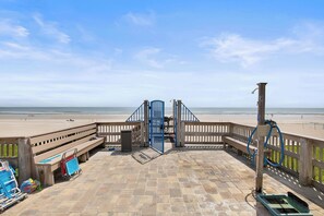 A beachside promenade with a wooden fence, benches, and a gate leading to the beach. - 🏊🥽🌴Ebb Tide 406 | NSB's Finest | New Pool + Sundeck + Beach Access (New Smyrna Beach)